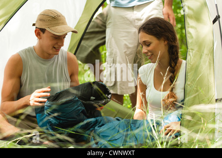 Young couple unrolling sleeping bag in tent Stock Photo