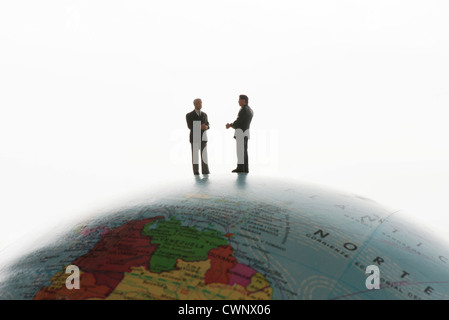 Businessman figurines standing on top of globe, silhouette Stock Photo