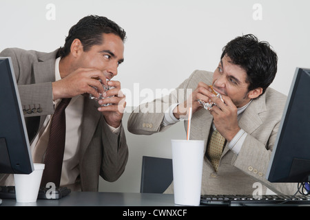 Businessmen eating fast food at desk in office Stock Photo