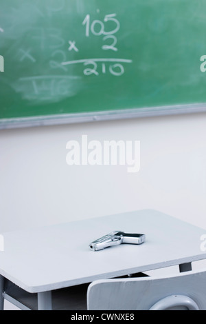 Handgun on desk in school classroom Stock Photo