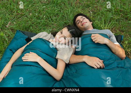 Young couple sharing sleeping bag in field Stock Photo