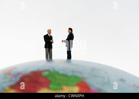 Businessman figurines standing on top of globe Stock Photo
