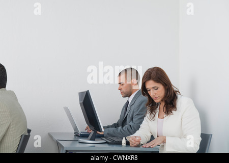 Woman applying nail polish in office while colleagues work Stock Photo