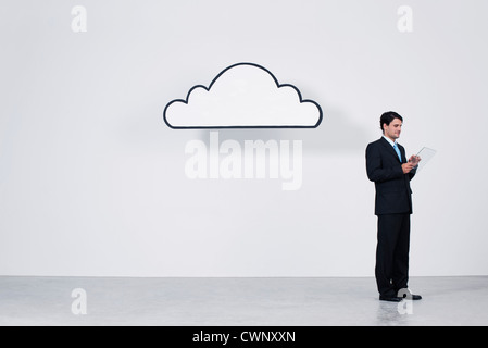 Businessman using digital tablet beneath cloud representing cloud computing Stock Photo