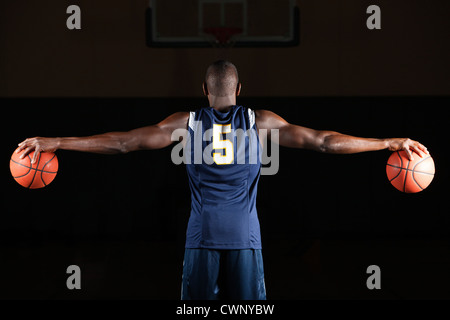 Basketball player holding basketballs in both hands, rear view Stock Photo