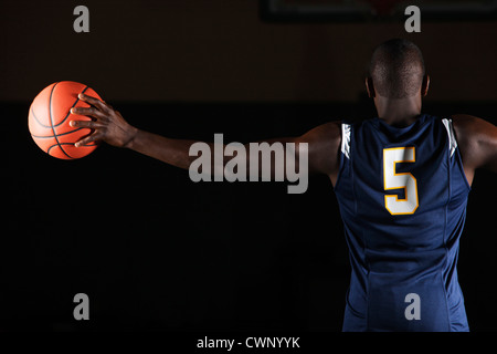 Basketball player holding basketball in hand, rear view Stock Photo