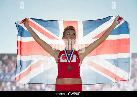 Young female medalist holding up British flag Stock Photo