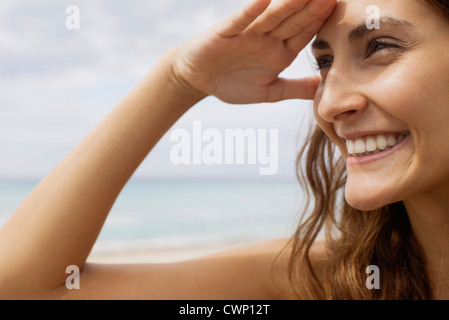 Woman at the beach, shading eyes to look at view Stock Photo