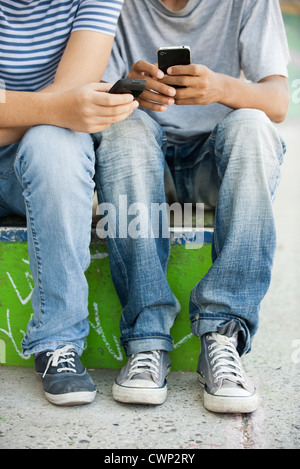Young men using cell phones, low section Stock Photo