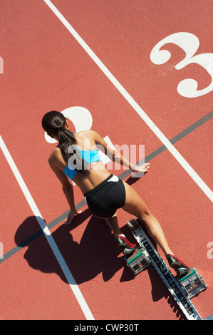 Female athlete in starting position on running track, rear view Stock Photo