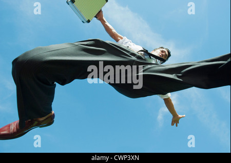 Businessman jumping in air carrying briefcase, directly below Stock Photo