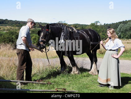 Young man and woman in period costume with heavy horse Beamish Museum, north east England, UK Stock Photo