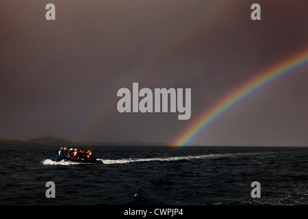 A zodiac inflatable boat in front of a double rainbow near James Island, Galapagos Stock Photo