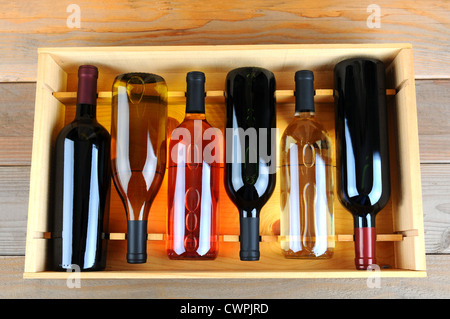 A wooden case of assorted wine bottles without labels on a wood plank winery floor. Horizontal format overhead view. Stock Photo