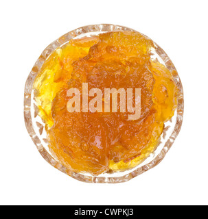 Top view of a glass dish filled with orange marmalade on a white background. Stock Photo