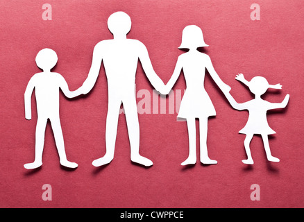 Cardboard figures of the family on a red background. The symbol of unity and happiness. Stock Photo