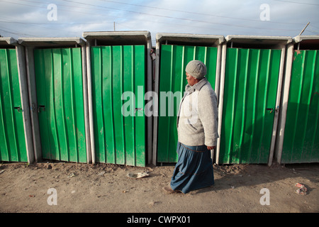 Woman Walking Past Toilets in Khayelitsha, South Africa Stock Photo