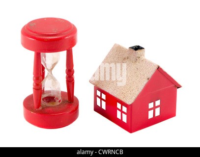 Red house imitation and broken sand glass clock isolated on white background. Real estate bubble collapse. Stock Photo