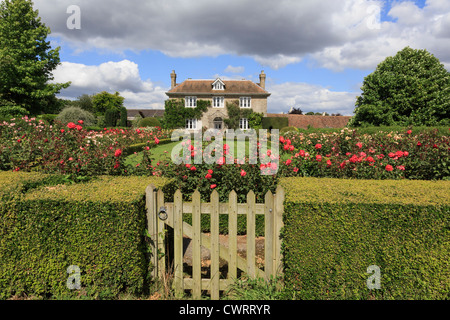 Hedge with gate to rose garden in front of a 19C English country house in summer. Pluckley, near Ashford, Kent, England, UK Stock Photo