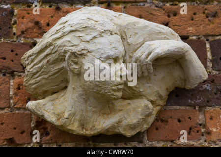 Stone sculpture of a Beautiful Lady on a red brick wall Garden Ornament Stock Photo