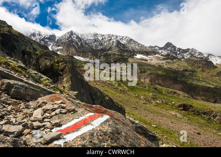 A painted marker shows the way on the lower slopes of Gemshorn near Saas Fee in Switzerland. Stock Photo