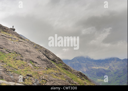 Man stands on boulder at the top of a mountain Stock Photo