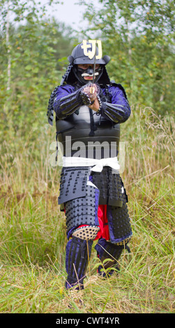 Man in Japanese medieval samurai armor (tosei-gusoku) standing in combat position with Japanese sword katana Stock Photo