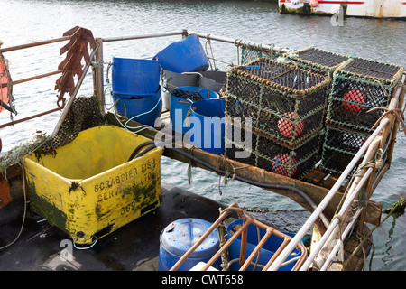 new lobster pots piled up in the back of a small fishing boat at John O'Groats harbour scotland uk Stock Photo