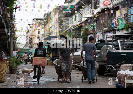 Thai worker pulling/pushing carts in the street around Pak Klong Talad (flower market) in Bangkok, Thailand Stock Photo