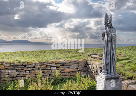 A statue of St Patrick, the patron saint of Ireland, stands among the ruins of an old church near Ballycastle, County Mayo Stock Photo