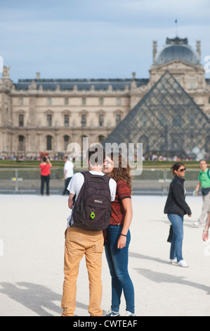 Paris, France - Young couple of tourists visiting town and taking photos of themselves by the Louvre Museum Stock Photo
