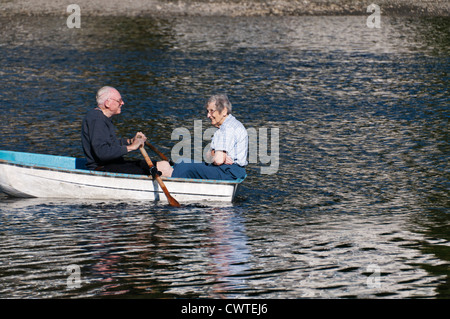 An active, smiling, mature senior adult couple enjoys a summer day on Puget Sound in their rowboat. Stock Photo