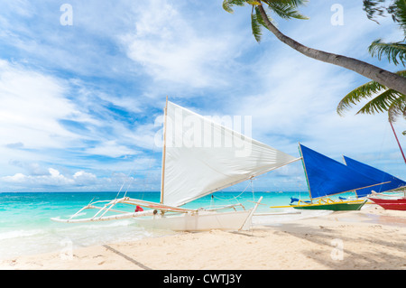 traditional paraw sailing boats on white beach on boracay island, Philippines Stock Photo