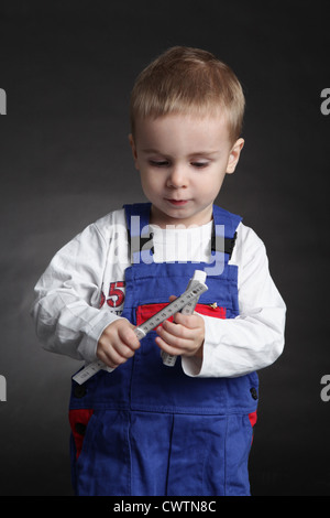 Boy wearing coveralls holding folding rule Stock Photo