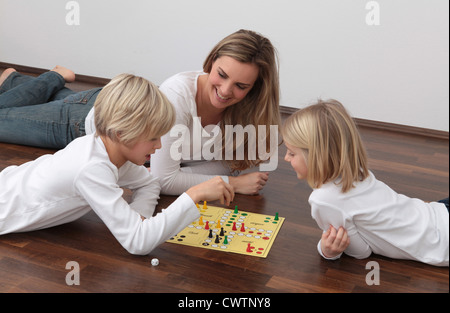 Mother and two children playing ludo on the floor Stock Photo