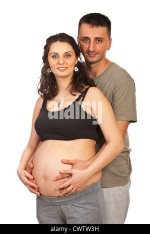 Happy pregnant couple standing in embrace and both holding hands on tummy isolated on white background Stock Photo