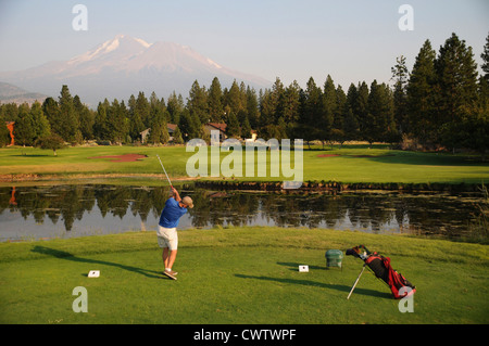 Man hitting across pond at Lake Shastina Golf Resort under the peak of Mount Shasta in Northern California Stock Photo