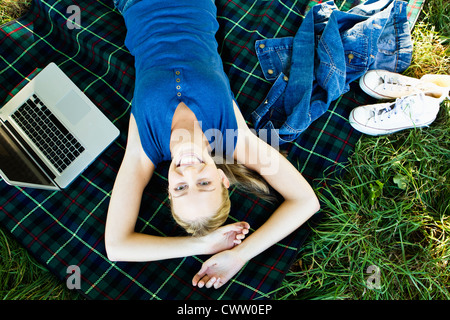 Smiling woman laying on blanket outdoors Stock Photo