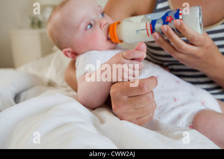 girl drinking bottle of milk laying on bed blond toddler Stock Photo - Alamy