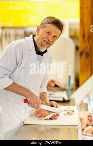 Butcher slicing meat at counter Stock Photo