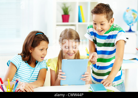 Portrait of happy classmates at workplace using digital tablet Stock Photo