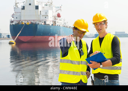 Two harbor engineers meeting, one pointing and explaining something to the other Stock Photo