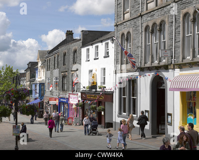 People tourists visitors and shops stores in the town centre in summer Market Square Keswick Cumbria England UK United Kingdom GB Great Britain Stock Photo