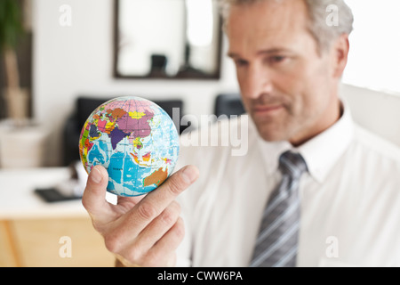 Businessman holding miniature globe Stock Photo