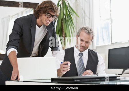 Businessmen working together at desk Stock Photo