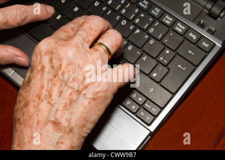 Old woman writes on one notebook Stock Photo