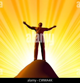 Belief and spirituality representing worship and the power of faith represented by a single man on the top of the mountain with Stock Photo