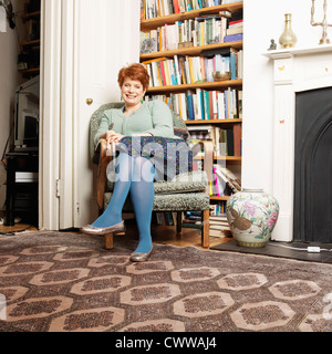 Smiling woman sitting in armchair Stock Photo