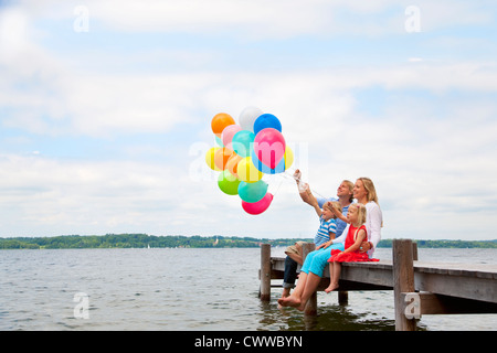 Family holding balloons on wooden pier Stock Photo