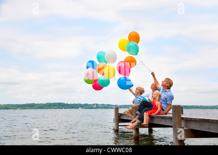 Family holding balloons on wooden pier Stock Photo